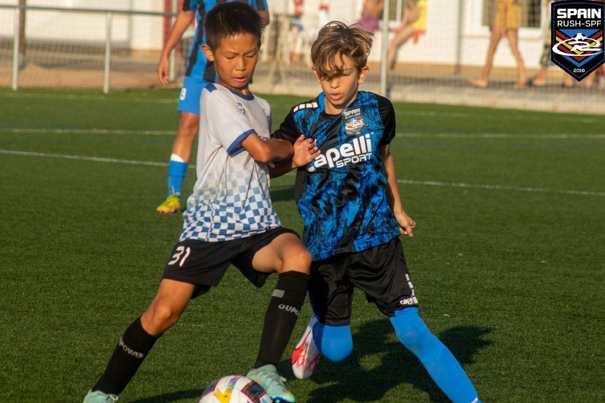 Two young boys are playing soccer on a field.