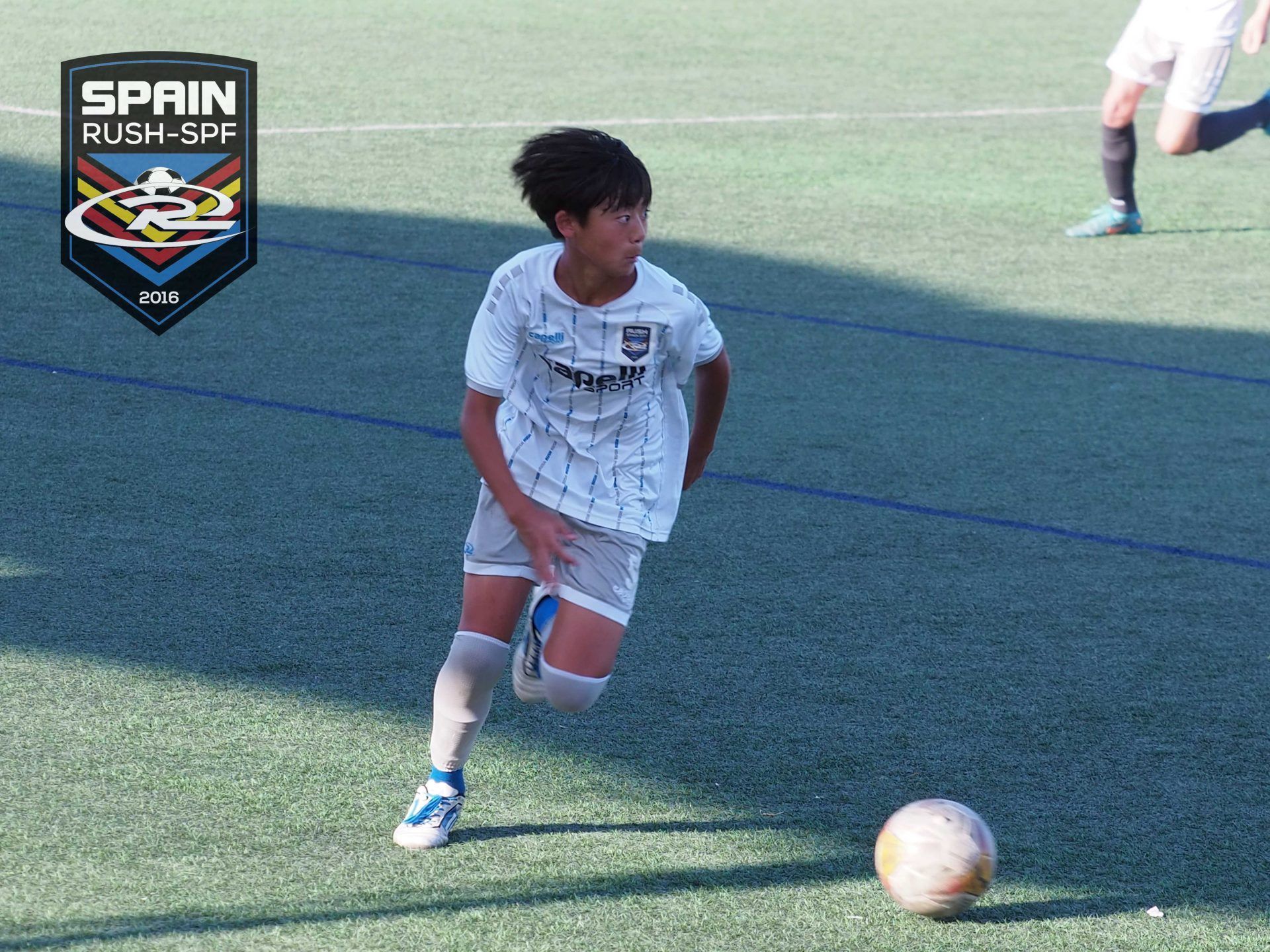 A young boy is playing soccer in spain