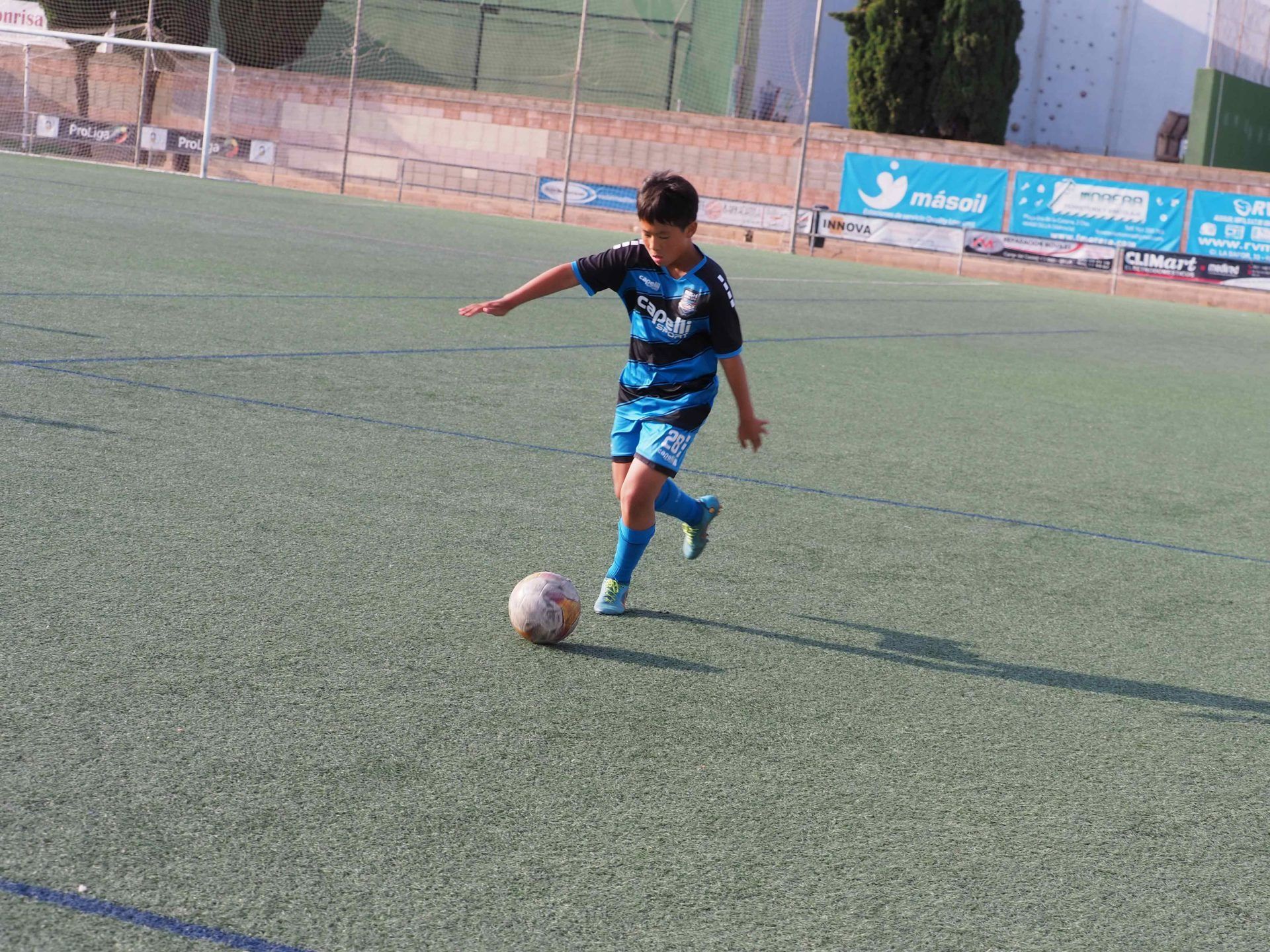 A young boy is kicking a soccer ball on a field.