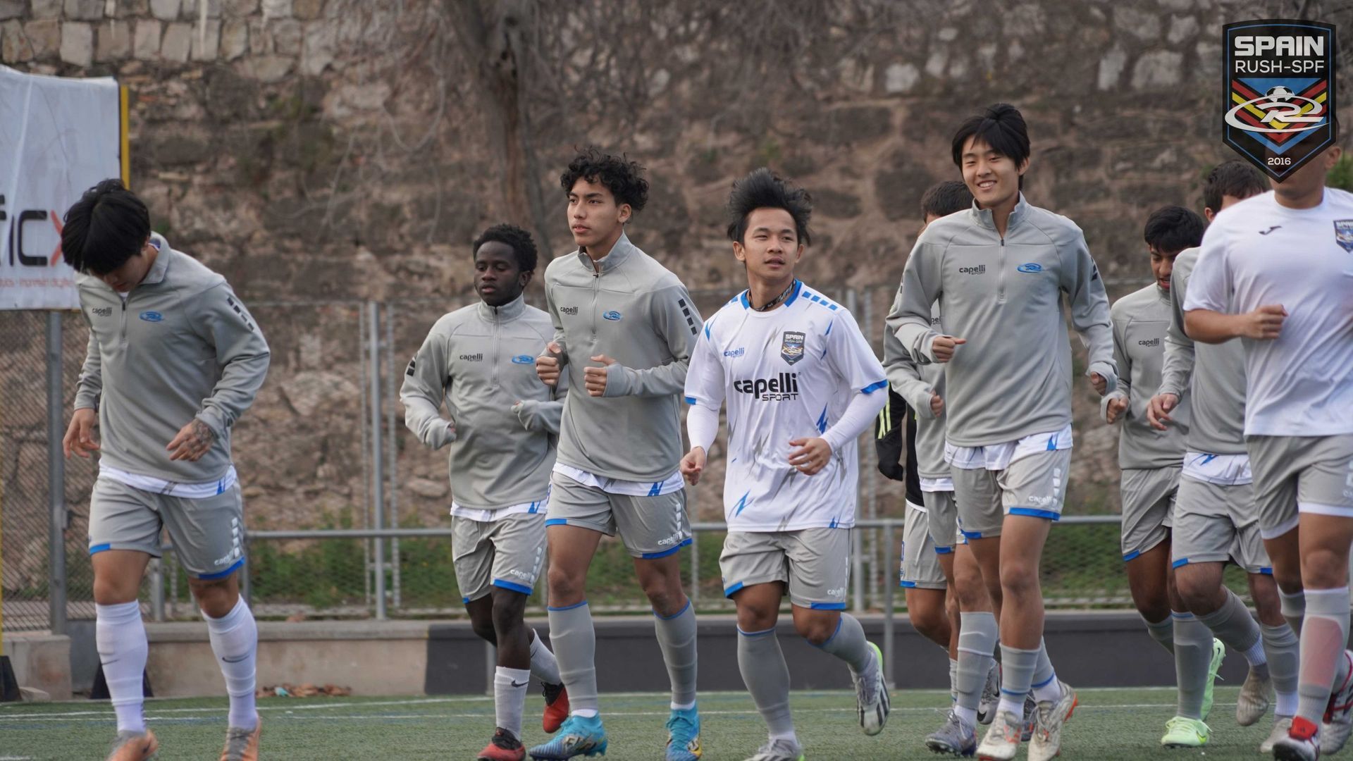 A group of young men are running on a soccer field.