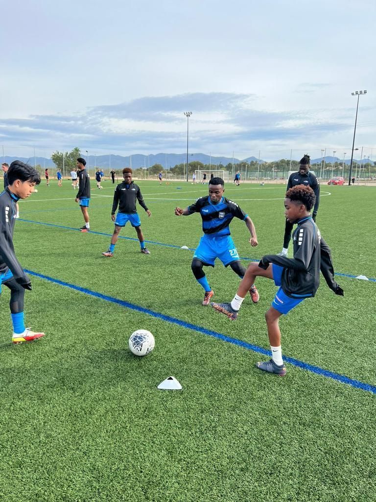 A group of Spain Rush boys are practicing soccer on a field.