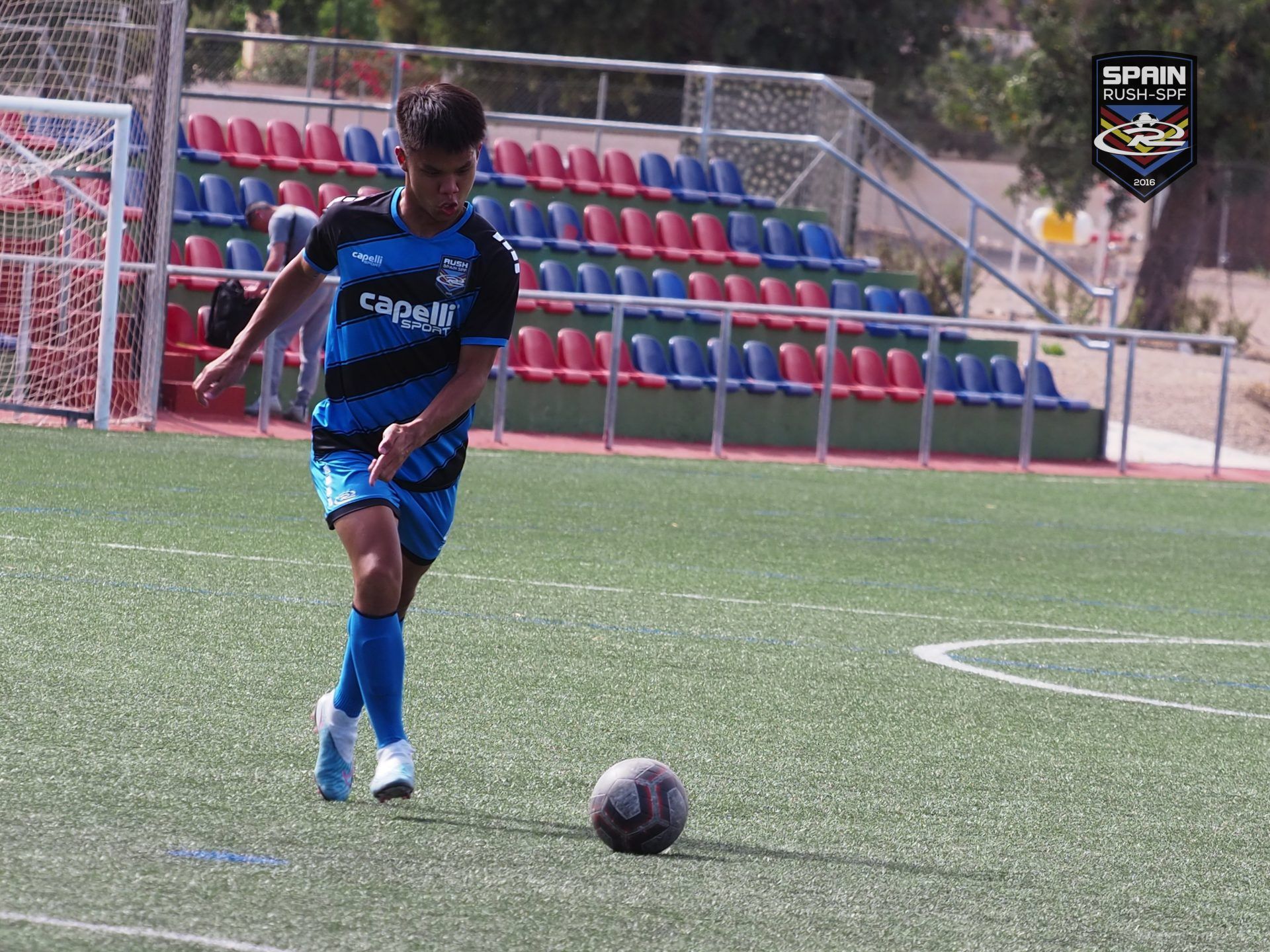 A young boy is kicking a soccer ball on a field.