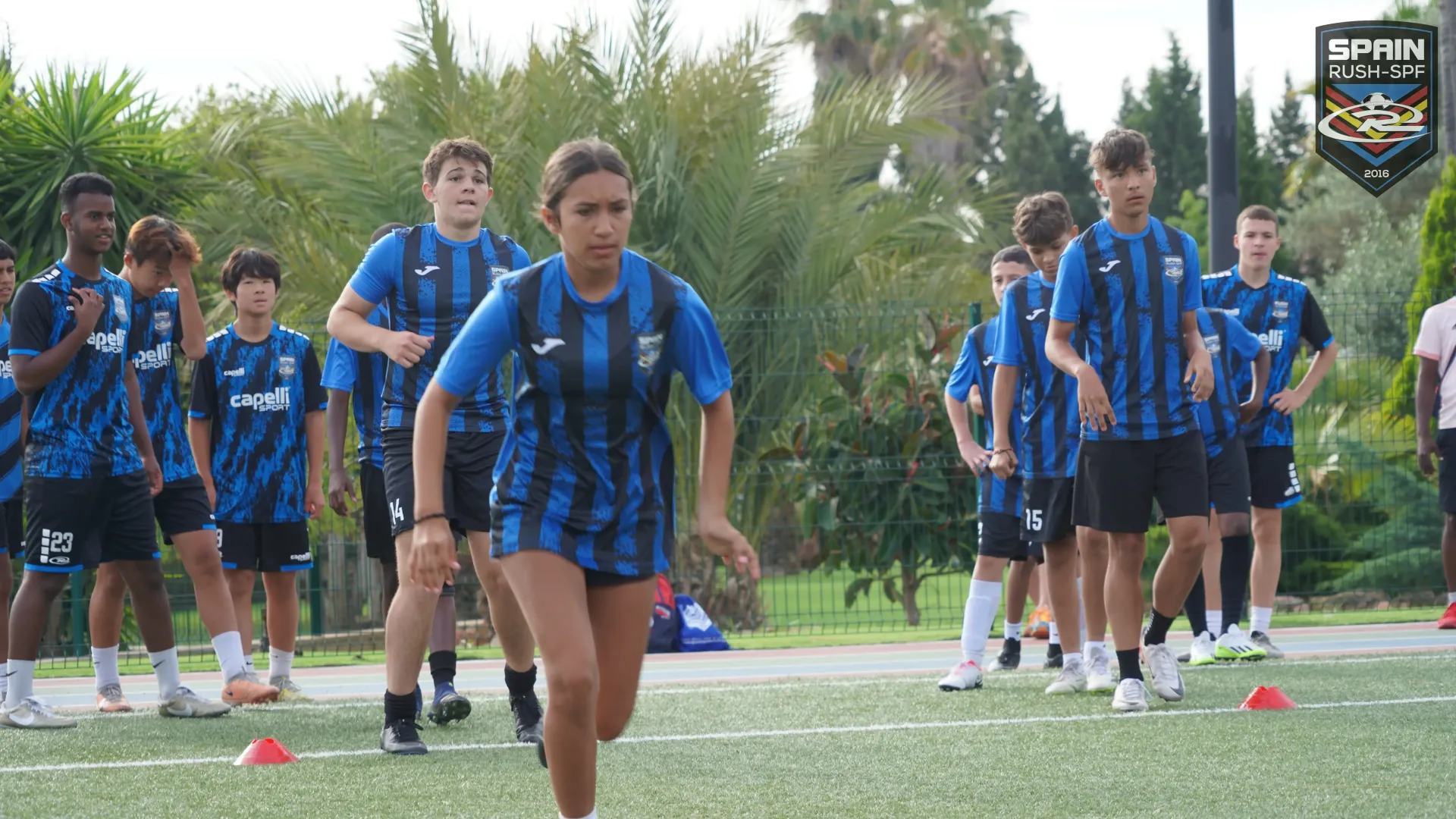 A group of young people are running on a soccer field.