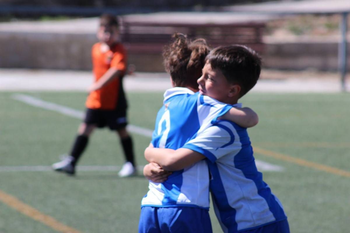 Two young boys hugging each other on a soccer field