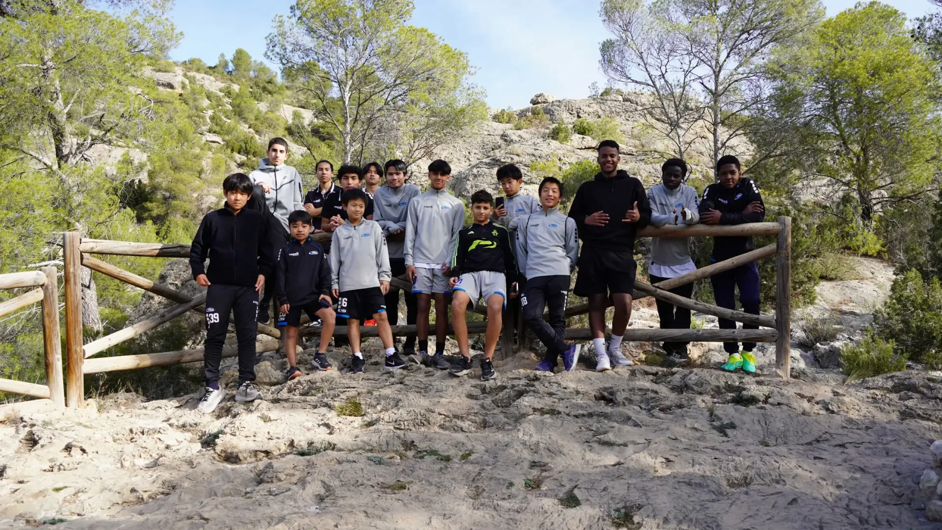 A group of young men are posing for a picture at a trail head.