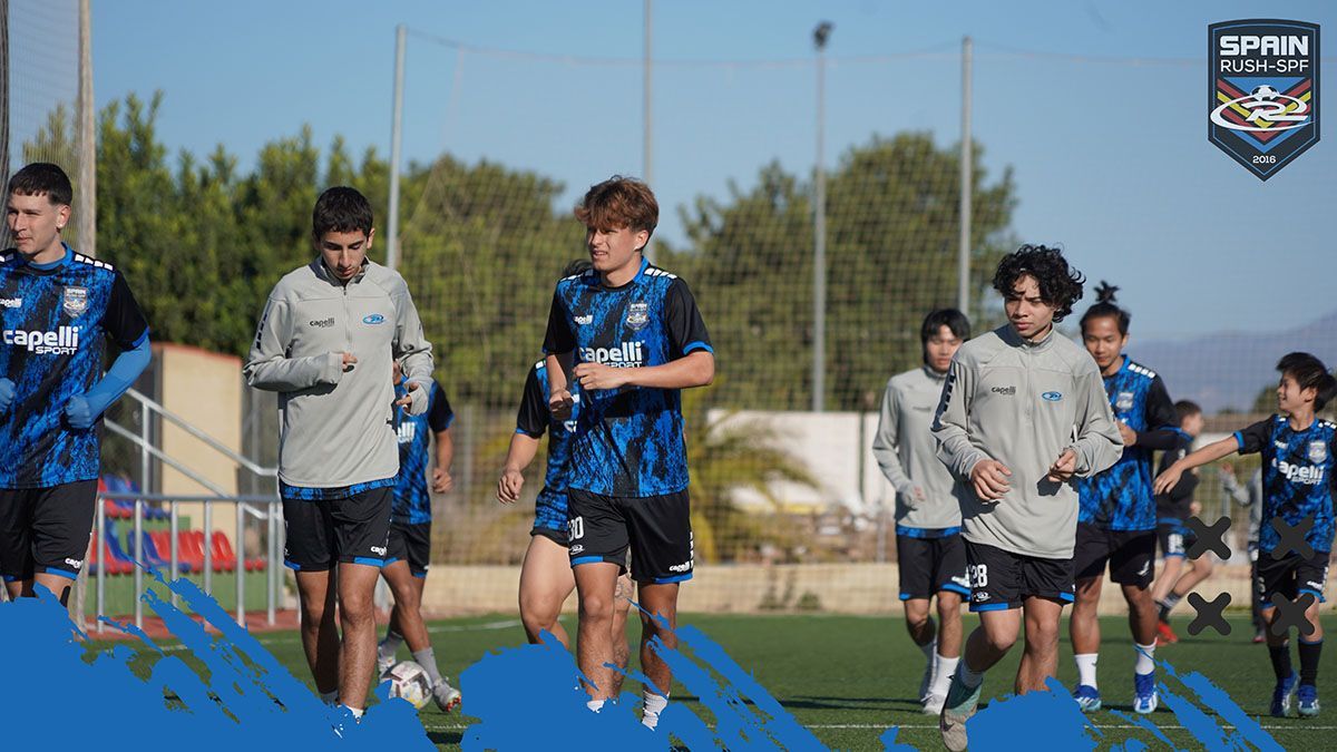 A group of young men are running on a soccer field.