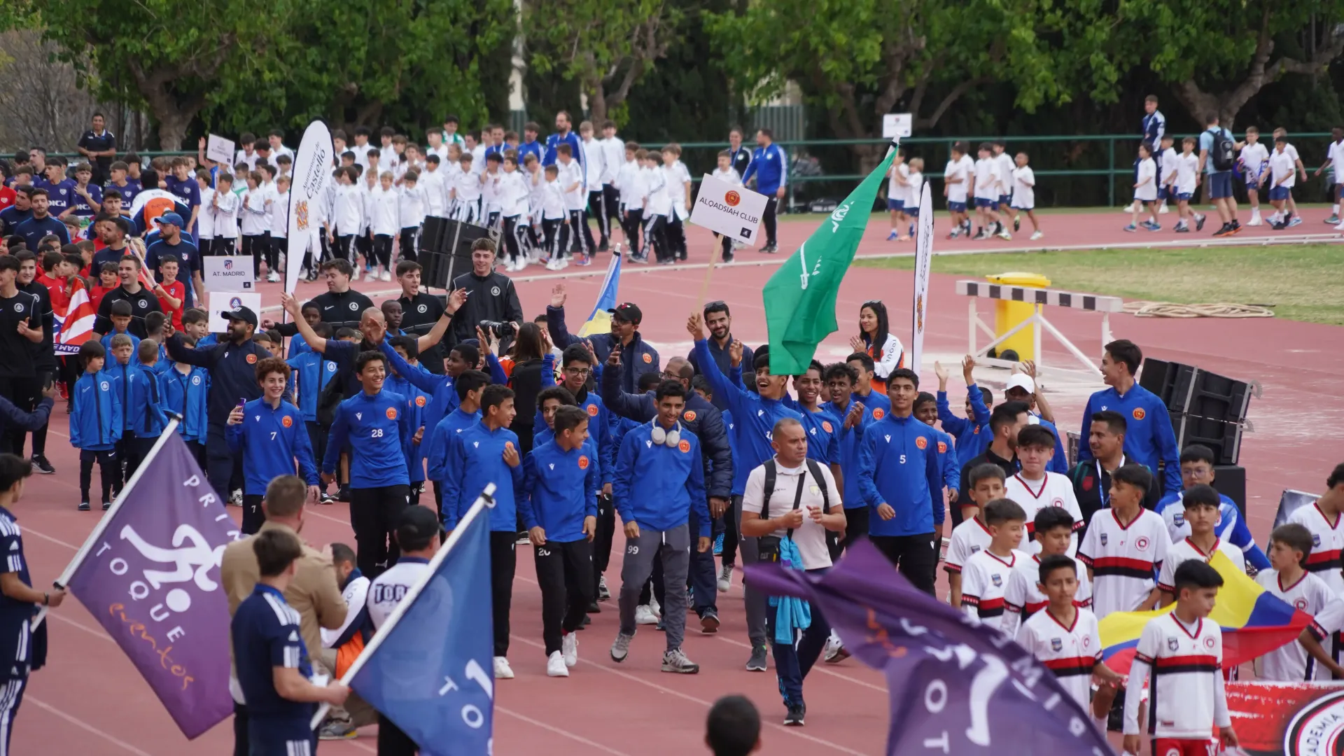 A group of people are walking down a track holding flags.