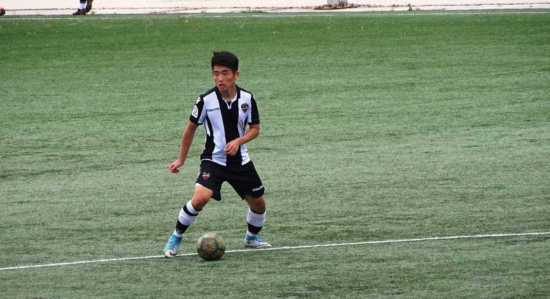 A young boy is playing soccer on a field.