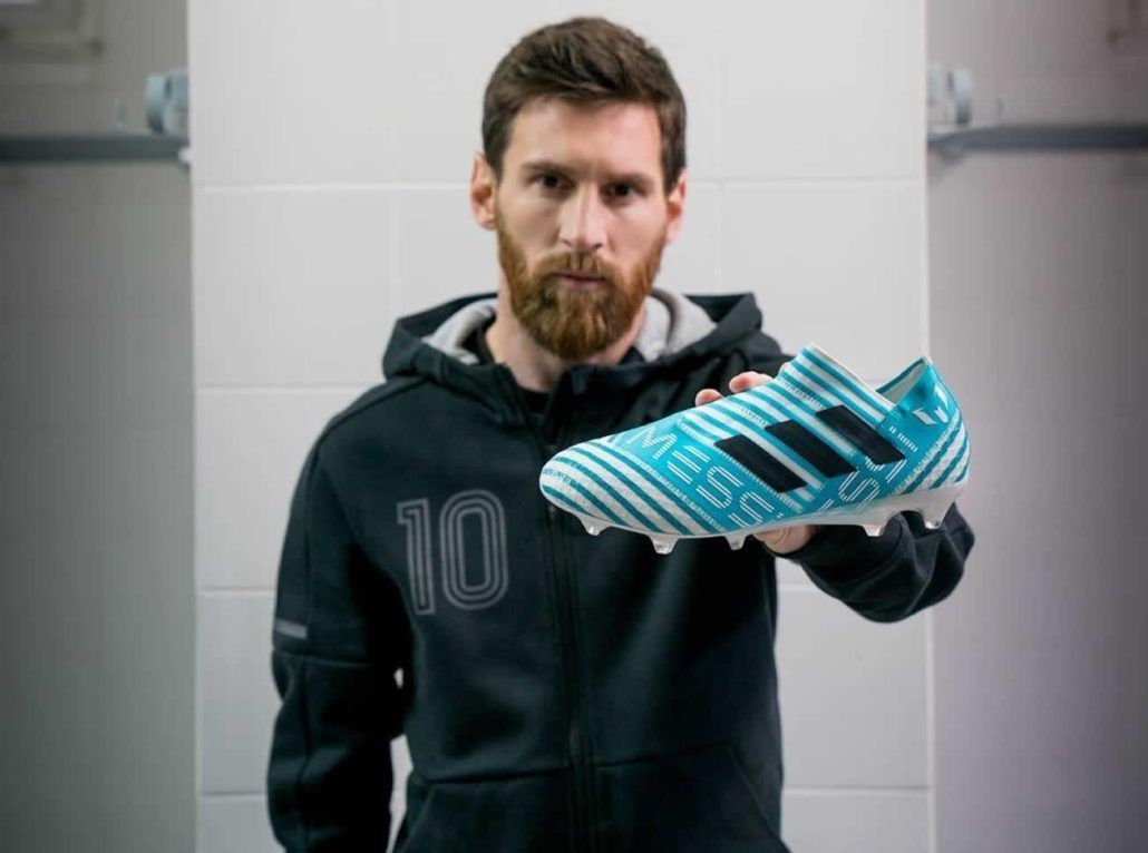 A man with a beard is holding a pair of soccer cleats.