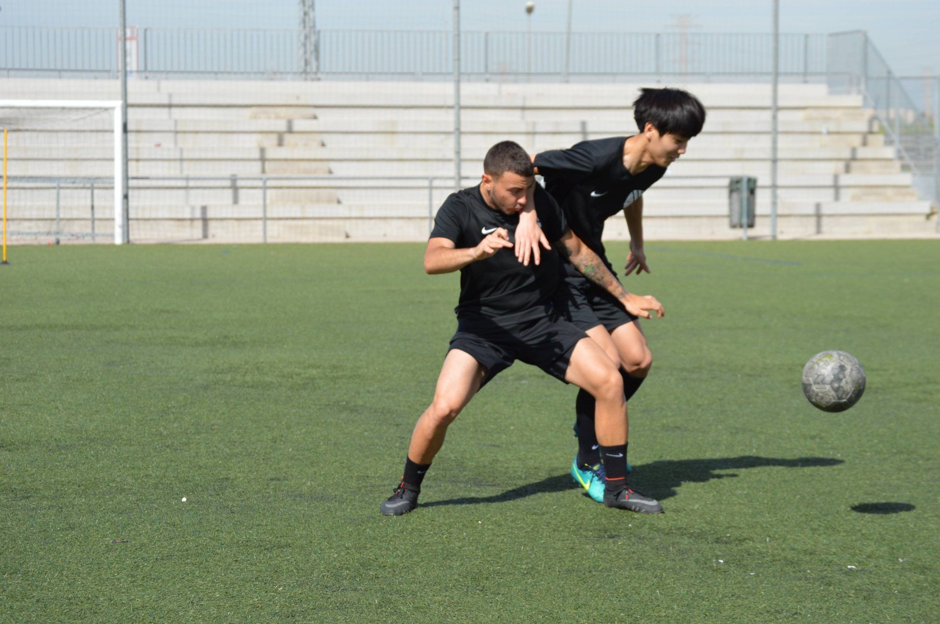 Two young men are playing soccer on a field.