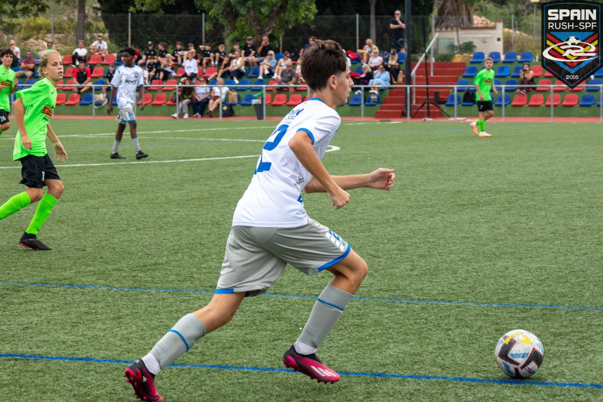 A young boy is kicking a soccer ball on a field.