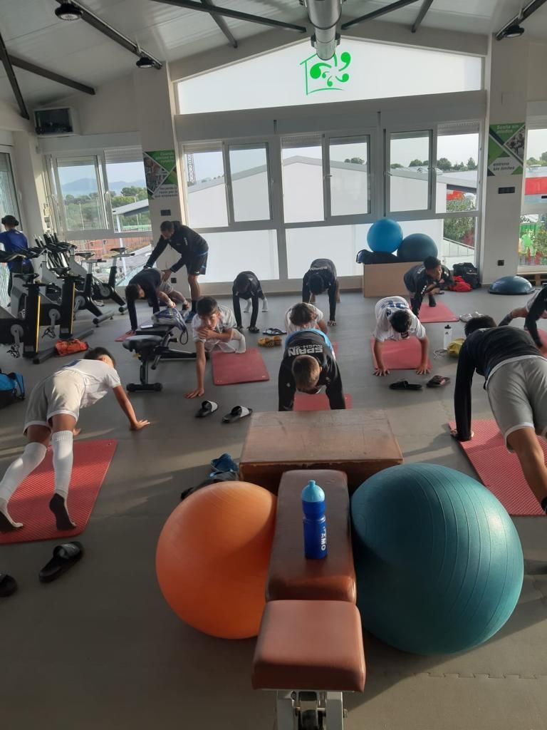 A group of people are doing stretching exercises in a gym.