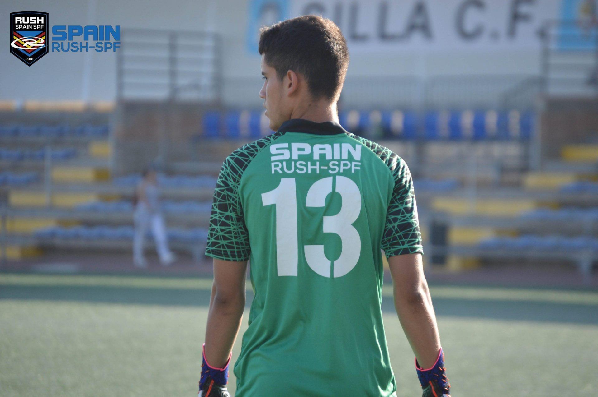 A soccer goalkeeper wearing a green jersey with the number 13 on it is standing on a field.