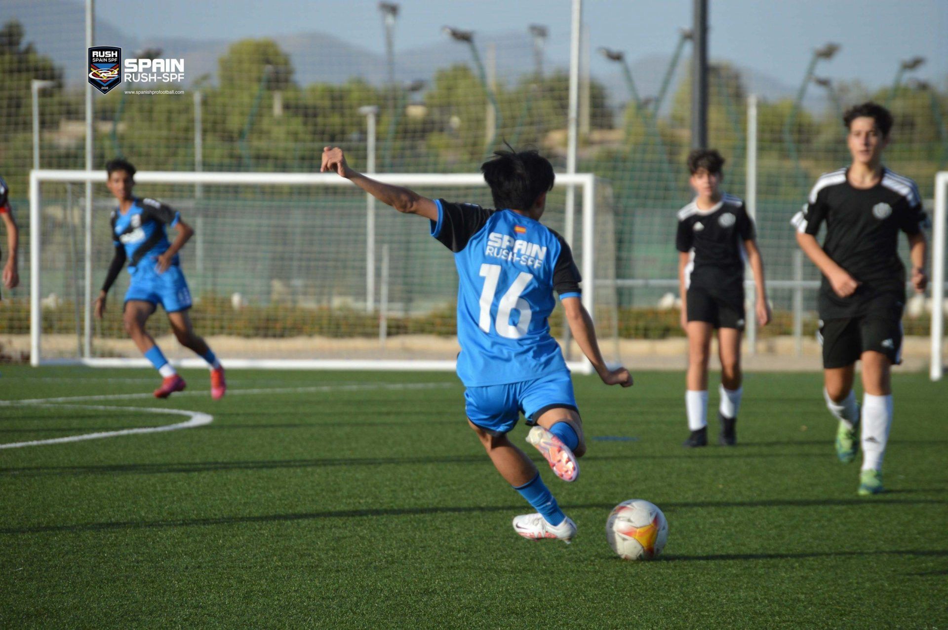 A young boy is kicking a soccer ball on a field.