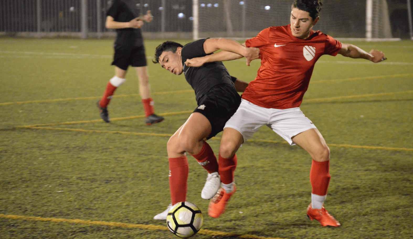 Two soccer players are fighting for the ball on a field.