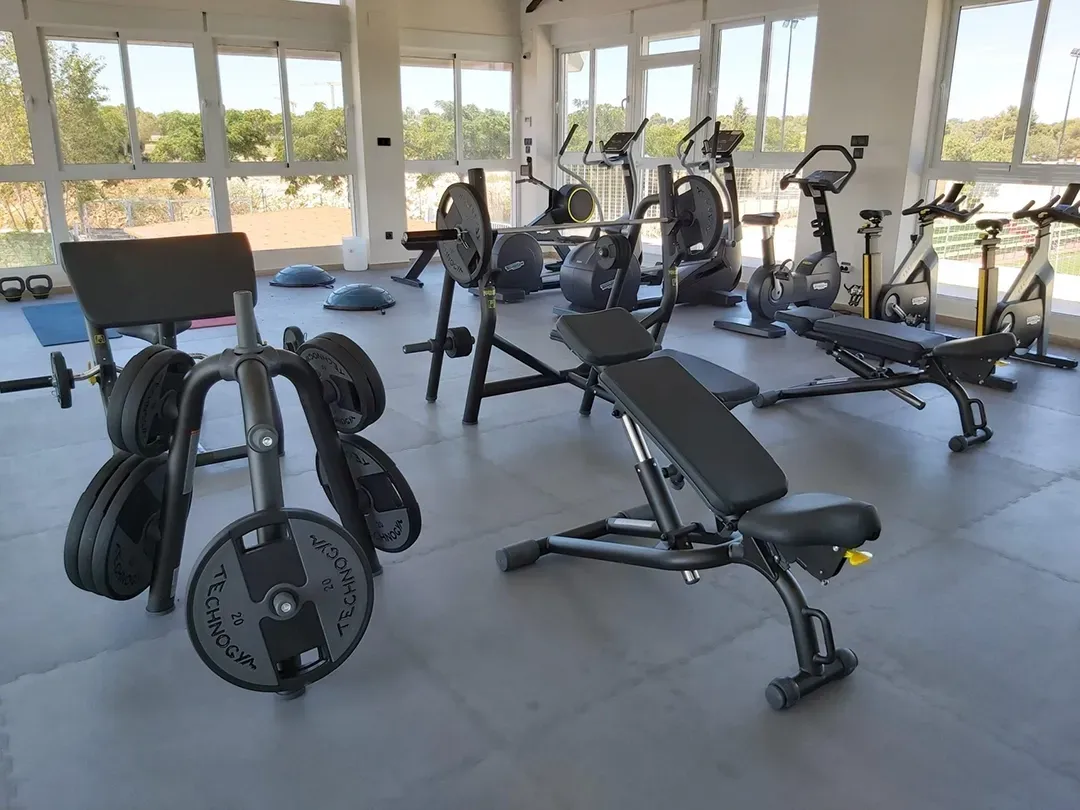A gym filled with lots of exercise equipment and a bench.
