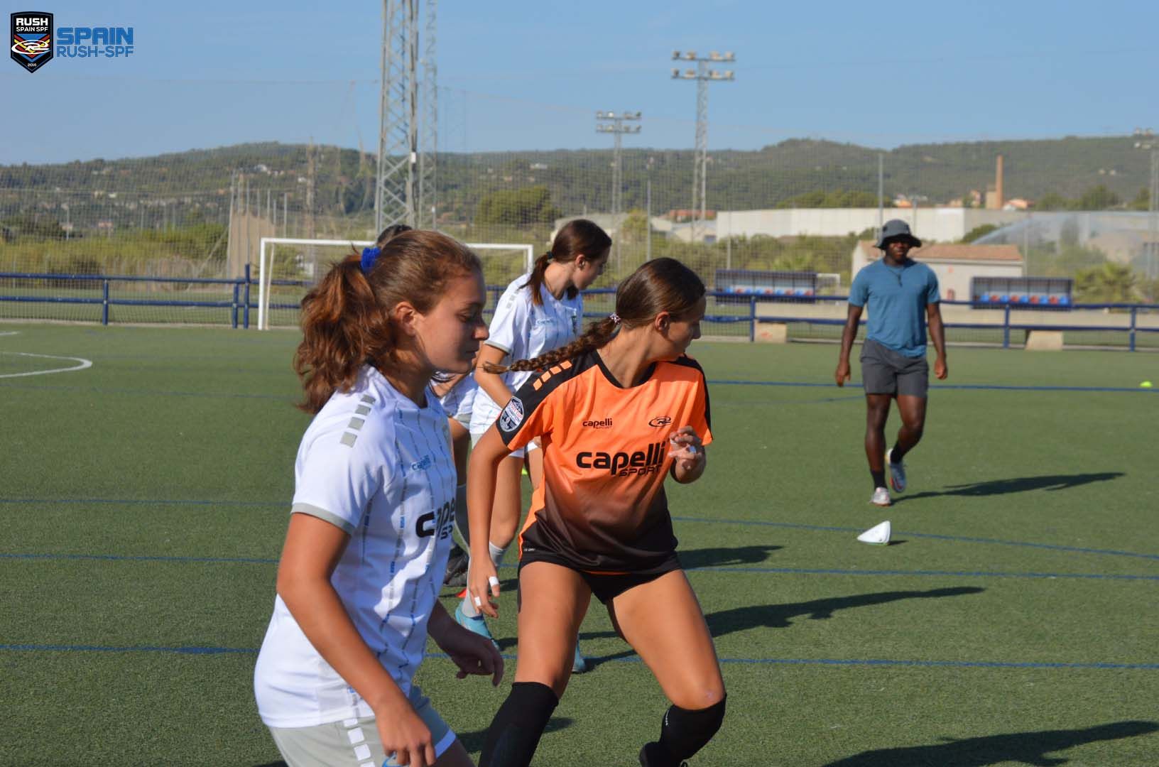 A group of young girls are playing soccer on a field.