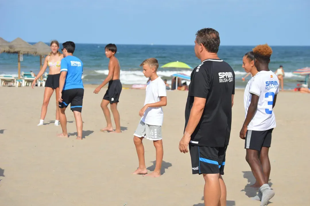 A group of soccer players are standing on a sandy beach.