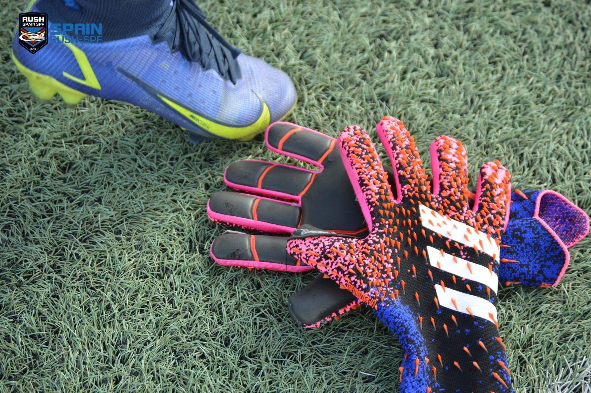 A person is wearing a pair of soccer cleats and a pair of goalie gloves.