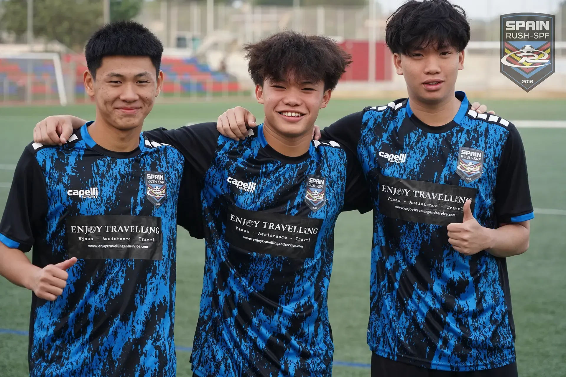 Three young men are posing for a picture on a soccer field.