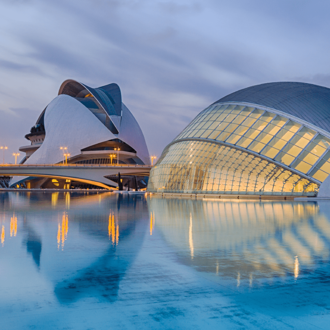 Two buildings are reflected in a body of water.