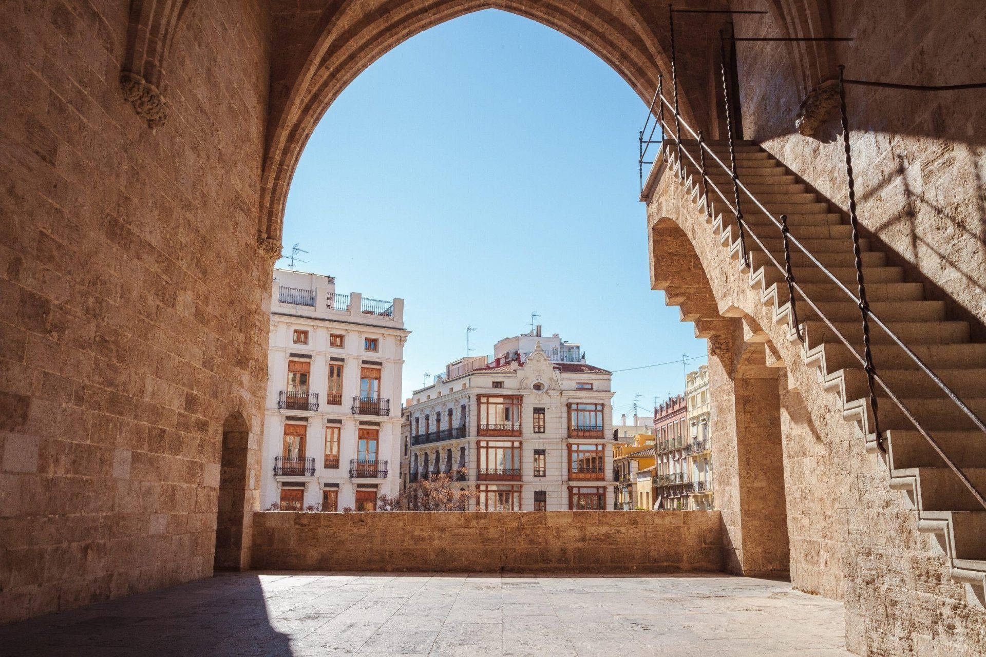 A view of Valencia through an archway with stairs leading up to it.