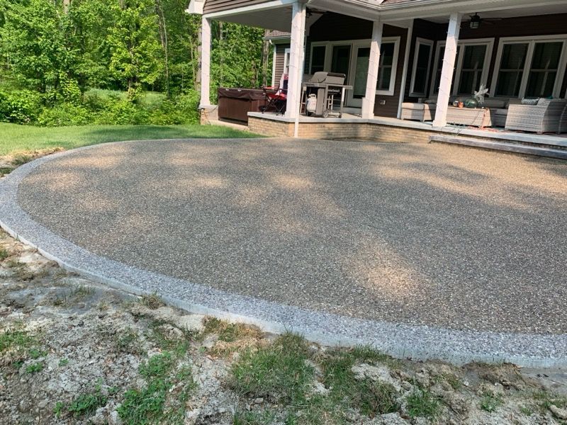 Paved park walkway with gray tiles and a red brick strip beside grass and trees