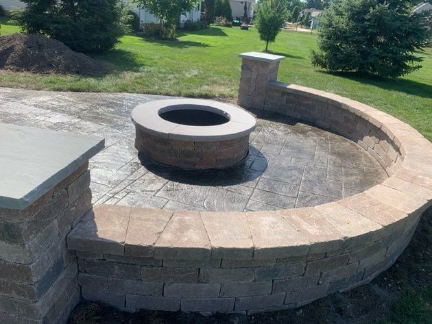 Stone backyard fire pit with circular seating wall and paved patio