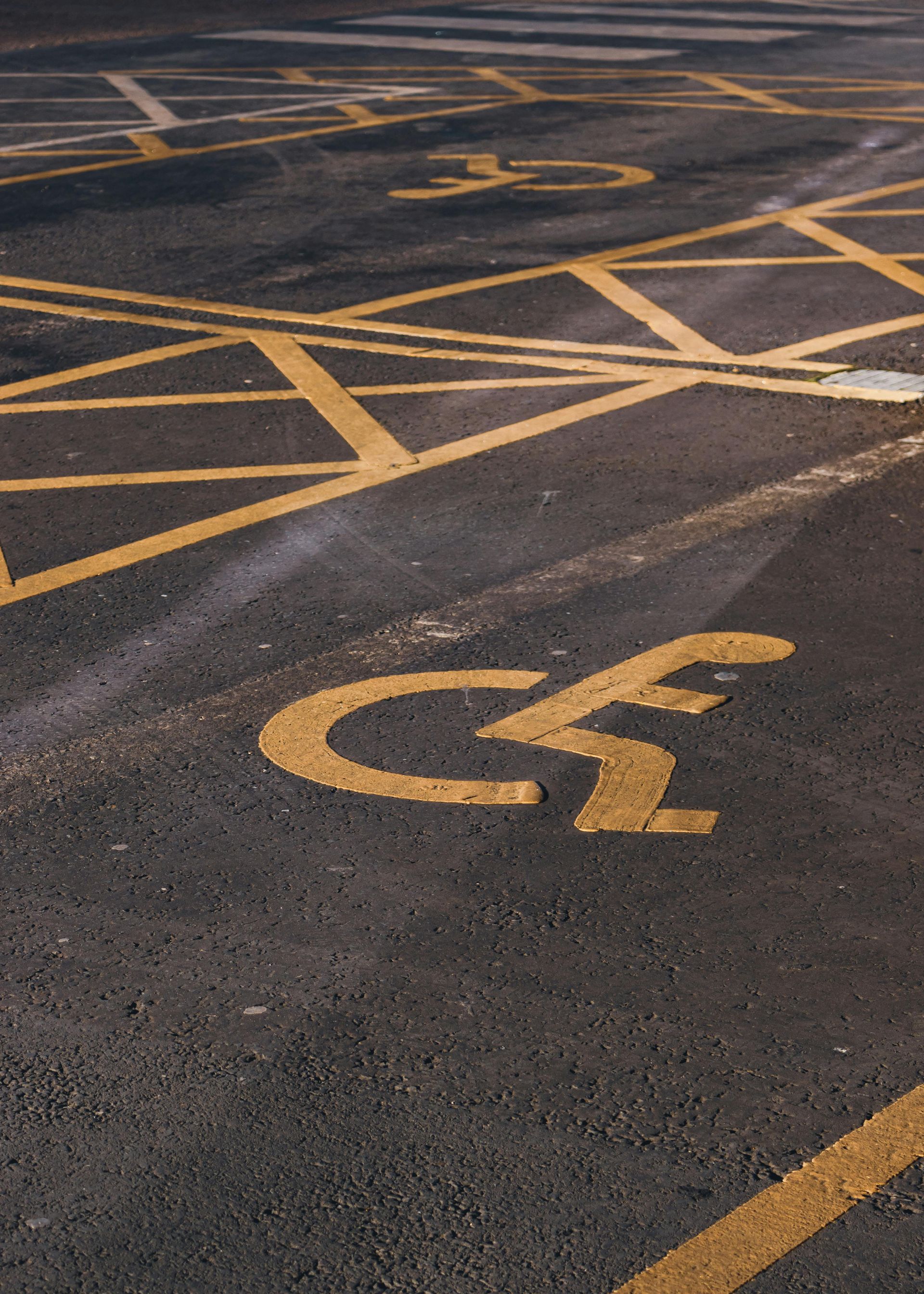 Yellow painted accessible parking symbols and crosshatch patterns on asphalt.