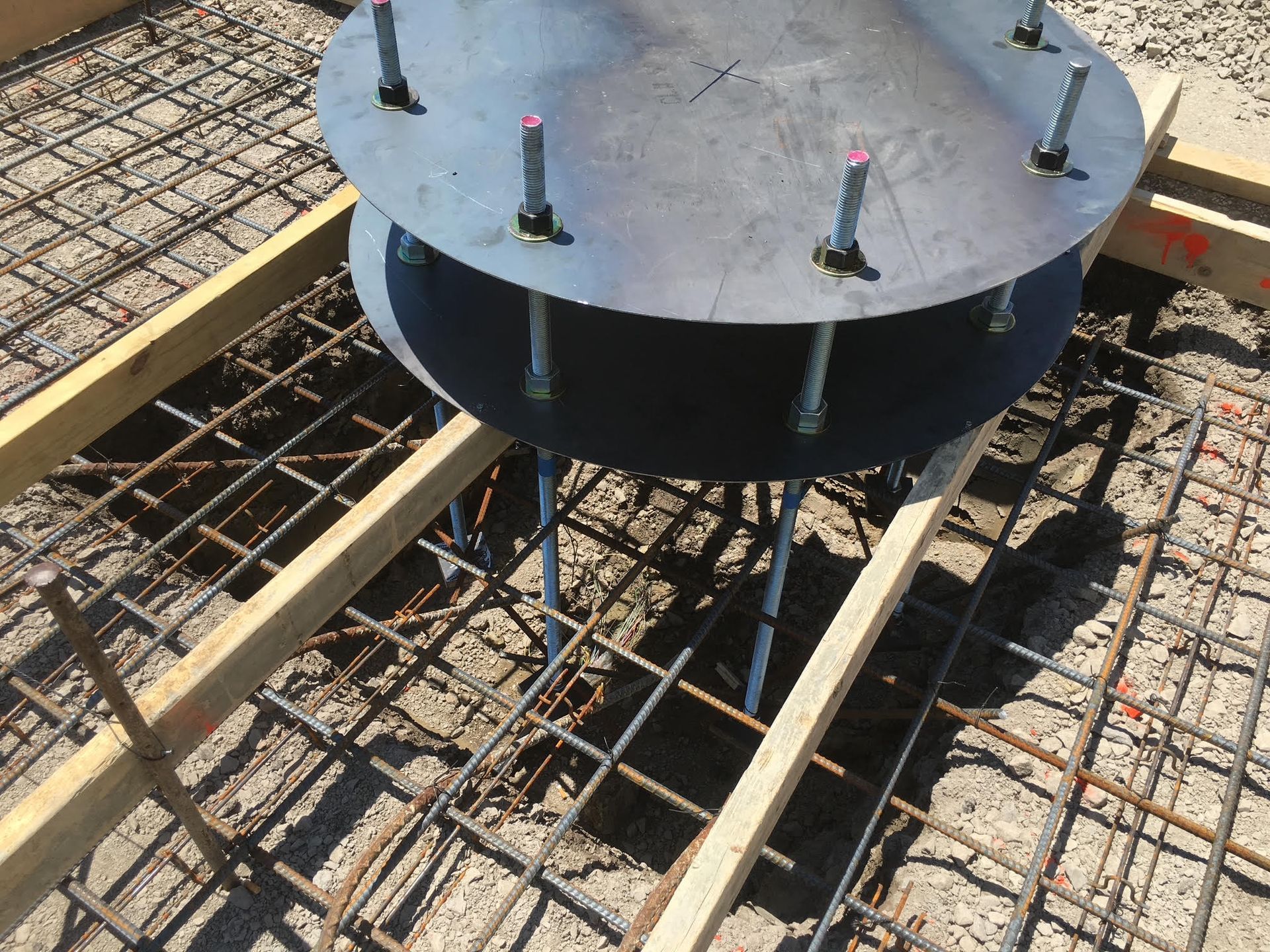 Metal fixture with bolts on rebar and wooden frame, ready for concrete pouring.