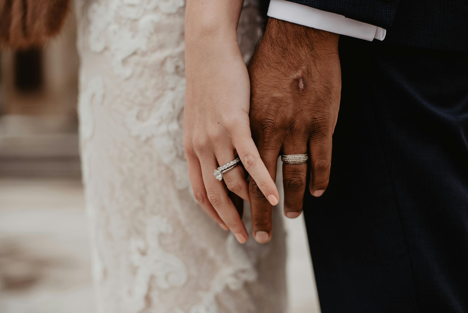 A bride and groom are holding hands with their wedding rings on their fingers.