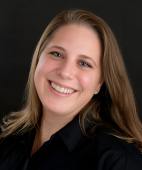 A woman in a black shirt is smiling for the camera.