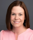 A woman in a pink shirt is smiling for the camera.