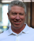 A man in a white shirt is smiling for the camera.