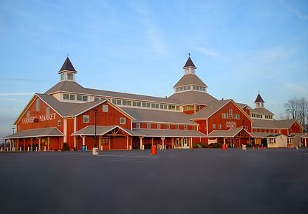 Red barn-like building with white trim and multiple cupolas under a blue sky.