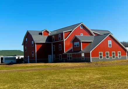 Red barn with gray roof against a clear blue sky.
