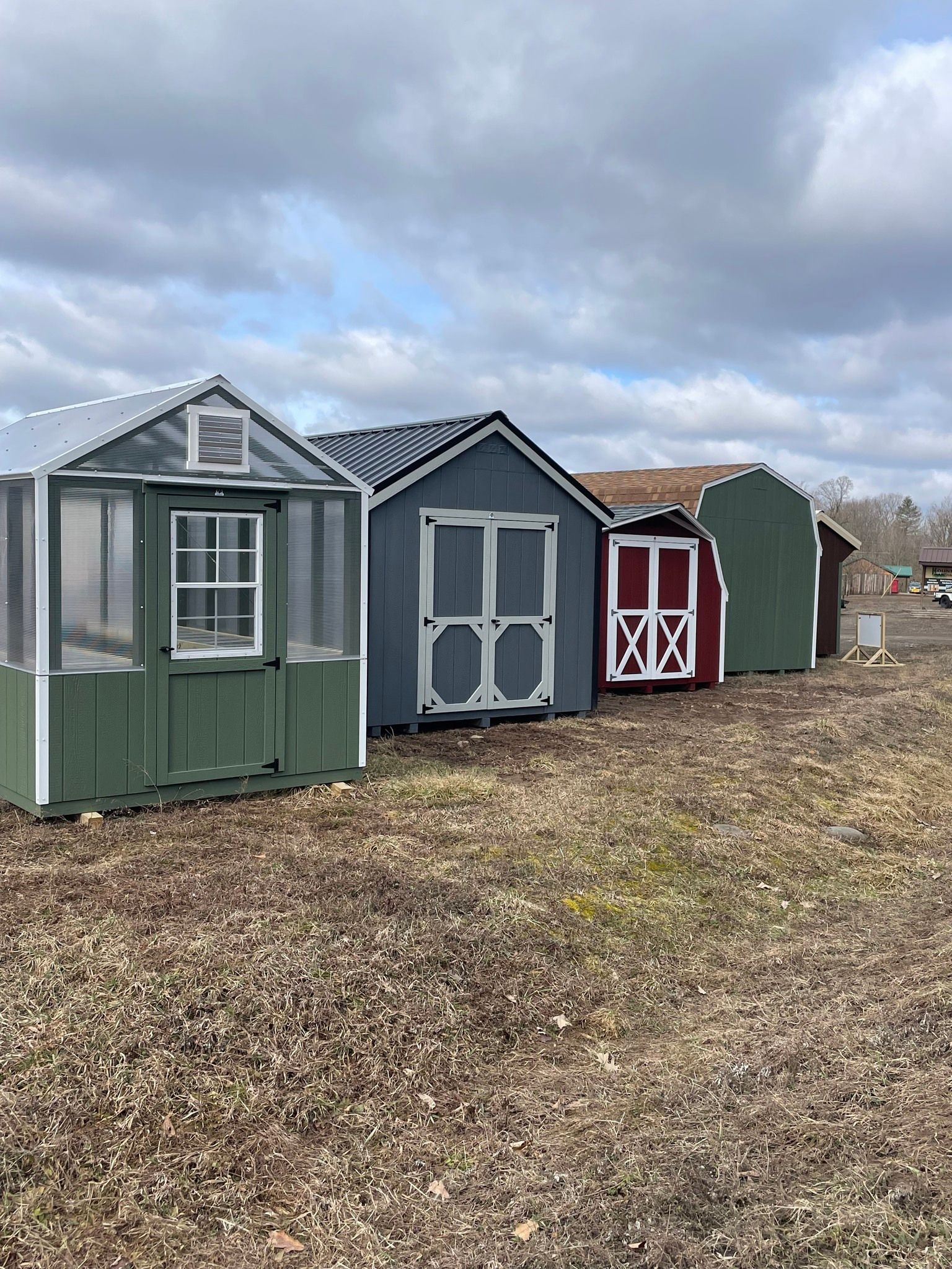 Row of colorful sheds on dry, brown ground under a cloudy sky.