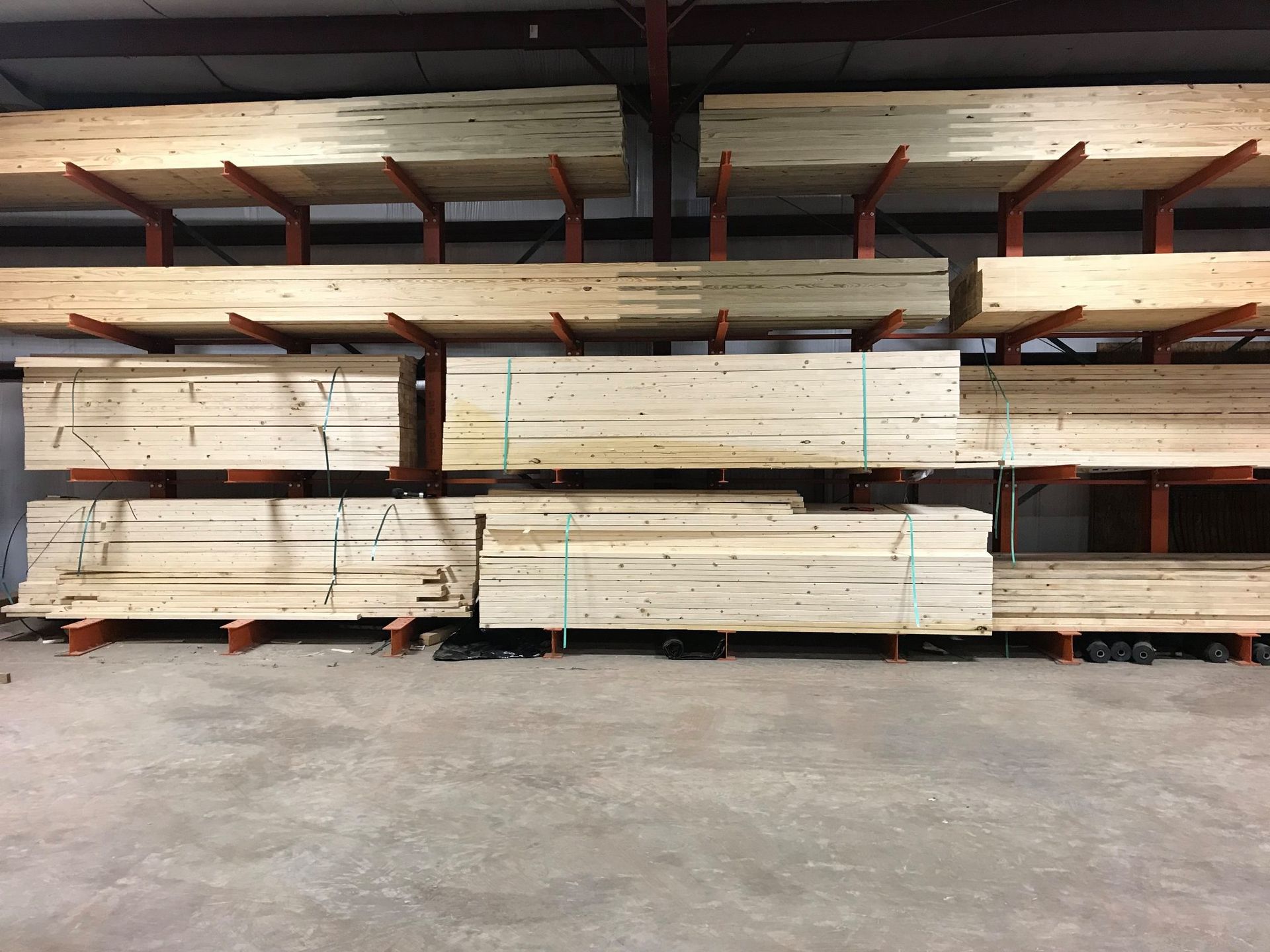 Lumber storage rack in a warehouse, filled with stacks of wooden planks, horizontal and angled.