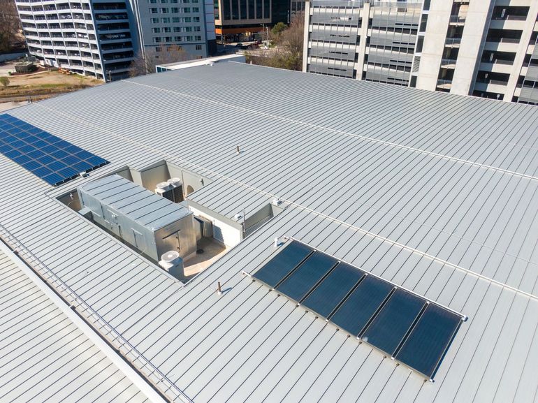 Rooftop with metal panels and solar panels, in a city with tall buildings.