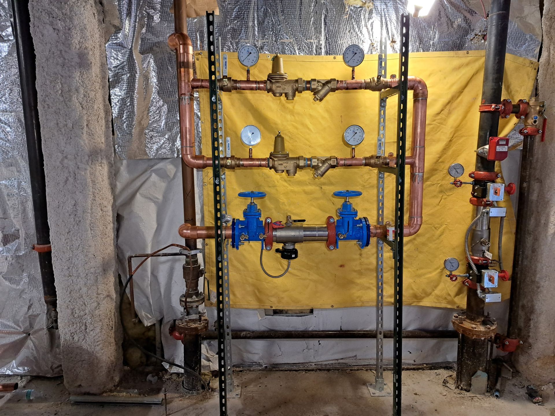 A bunch of pipes and valves are hanging on a wall