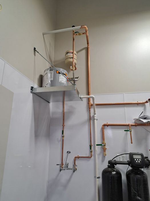 A person is fixing a pipe under a sink with a wrench.