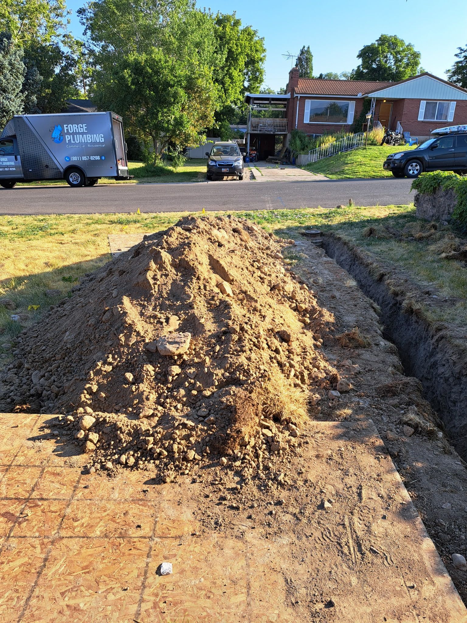 A pile of dirt is sitting next to a trench in front of a house.