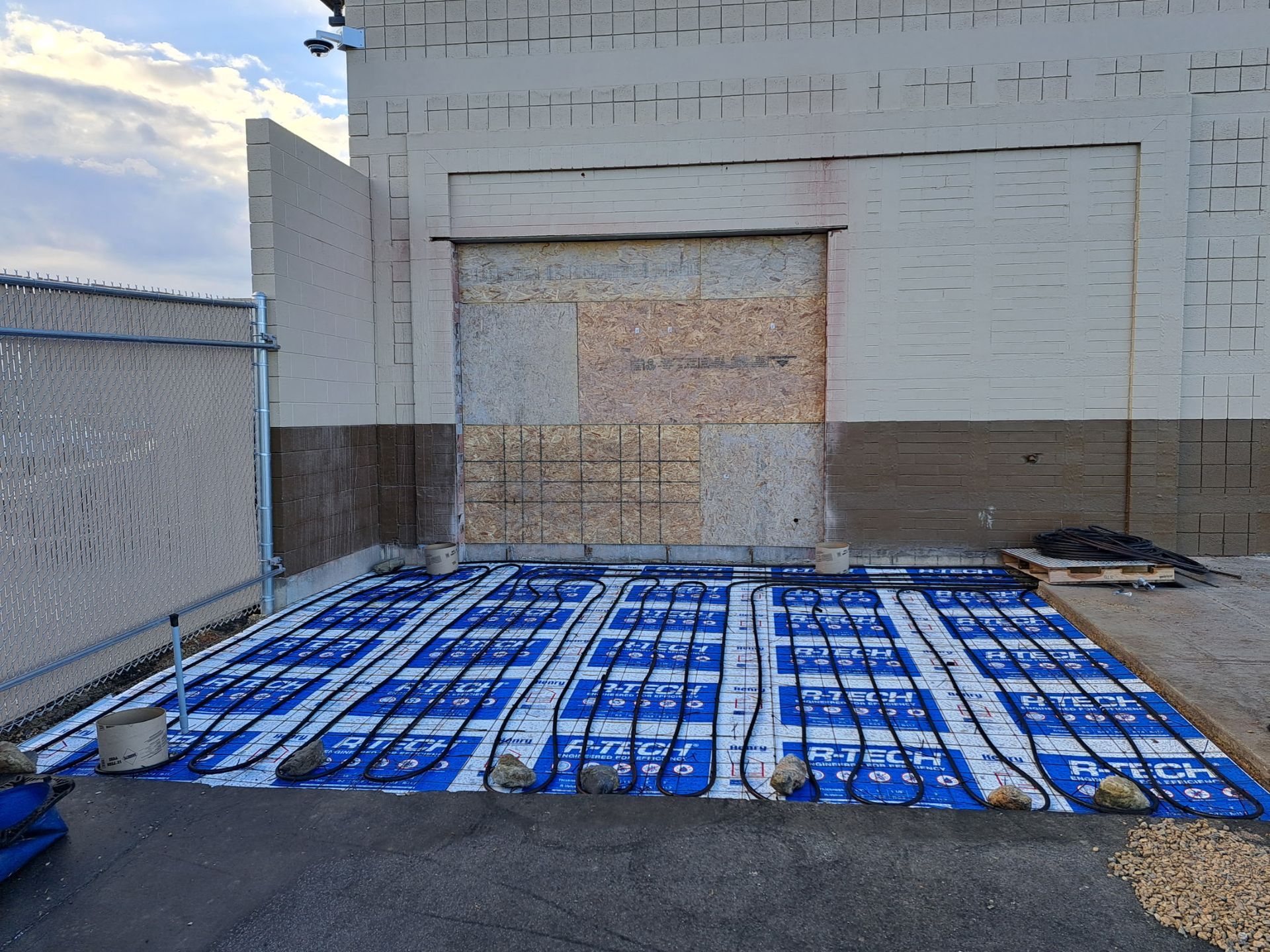 A building under construction with a blue tarp on the ground in front of it.