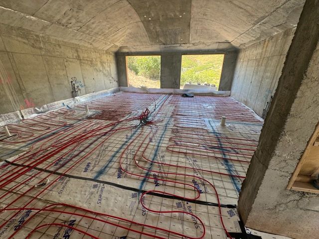 Two construction workers are working on a pipe in the dirt.