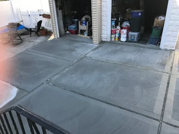 Newly poured concrete driveway sections, gray with smooth finish, leading to a garage.