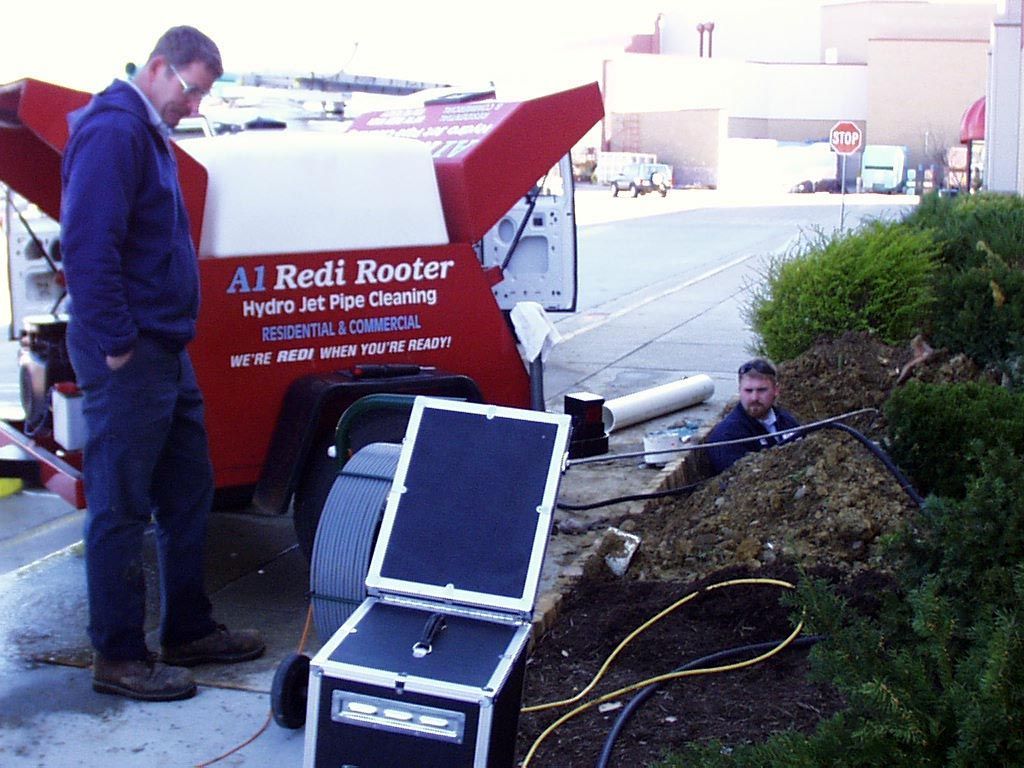 A man standing in front of a red rooter truck