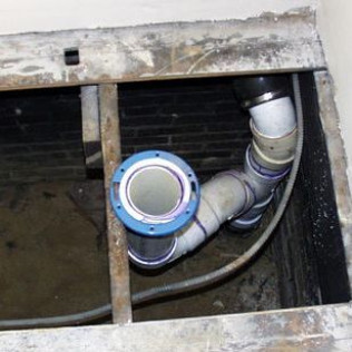 A bunch of pipes are coming out of a hole in the wall