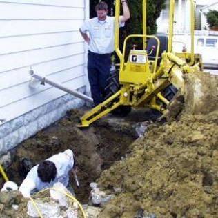 A man is standing next to a yellow machine that says g on it