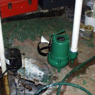 A green pump is sitting on the floor next to a hose.