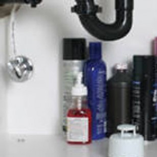 A bathroom sink filled with bottles of shampoo and soap.